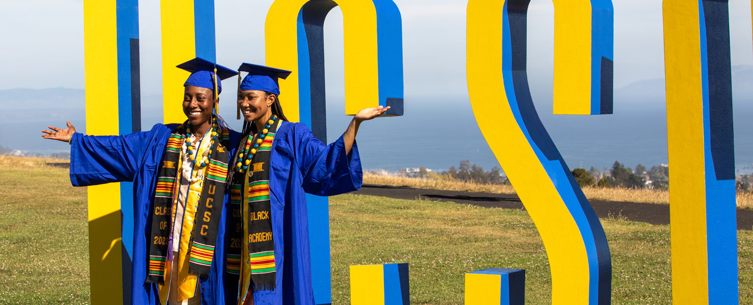 Graduating students pose in front of UCSC sign